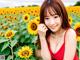 A woman in a red dress standing in a field of sunflowers.