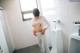 A woman standing in front of a urinal in a bathroom.