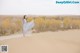 A woman in a long dress standing on top of a sand dune.