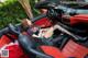 A woman sitting in the driver's seat of a red sports car.