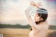 A naked woman wearing a white lace headband in a field.