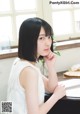 A woman sitting at a table with her hand on her chin.