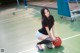 A woman kneeling on a basketball court holding a ball.