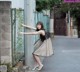 A woman leaning against a fence with her arms outstretched.