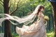 A woman in a wedding dress holding a bouquet of flowers in a forest.