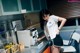 A woman standing in front of a coffee machine.