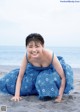 A woman in a blue dress sitting on the beach.