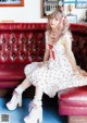 A woman sitting on a red couch wearing a white dress.