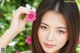 A woman holding a pink flower in front of her face.