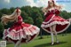 A woman in a red and white dress is dancing in a field.