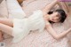 A woman laying on a bed in a white dress.