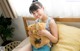 A young girl sitting on a bed holding two teddy bears.