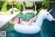 A woman laying on an inflatable unicorn floating in a pool.