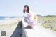 A woman in a kimono sitting on a concrete wall by the ocean.